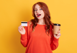 Mulher branca sorrindo ao segurar o Cartão Caju Benefícios