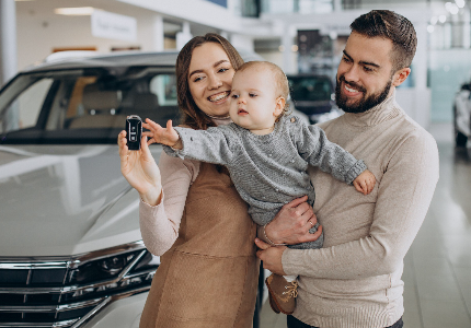 Familia con bebé recibiendo llaves de su auto nuevo en agencia, simbolizando seguridad y beneficios de los mejores seguros de auto.