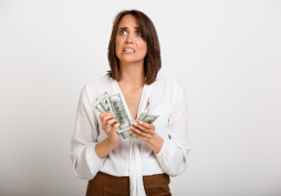 Mujer preocupada sosteniendo billetes en la mano, representando estrés financiero y riesgo de morosidad en tarjetas de crédito durante el fin de año