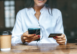 Pessoa usando cartão de crédito e celular para controle financeiro e compras online