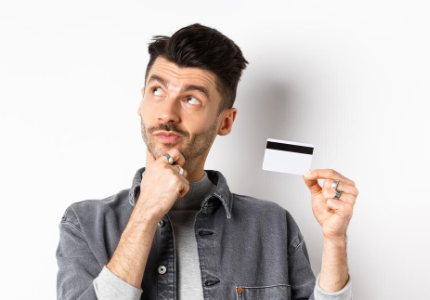 Homem pensando enquanto segura cartão de crédito na mão