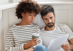 Casal analisando contas e despesas domésticas em casa com expressão de preocupação