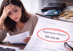 Mulher preocupada analisando contas e cartão de crédito com calculadora na mesa