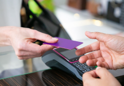 Pessoa segurando cartão de débito enquanto realiza pagamento no dia a dia